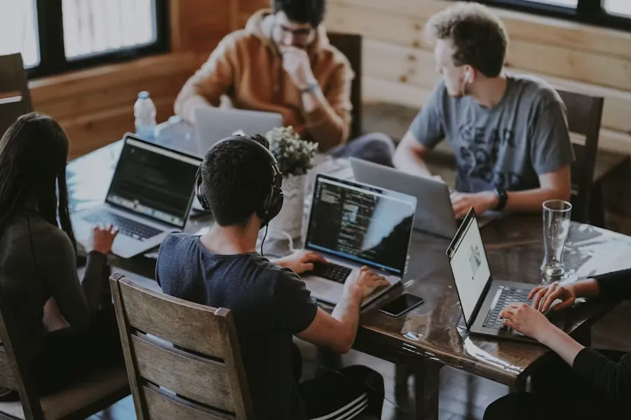 Engineers working at laptops around a shared table